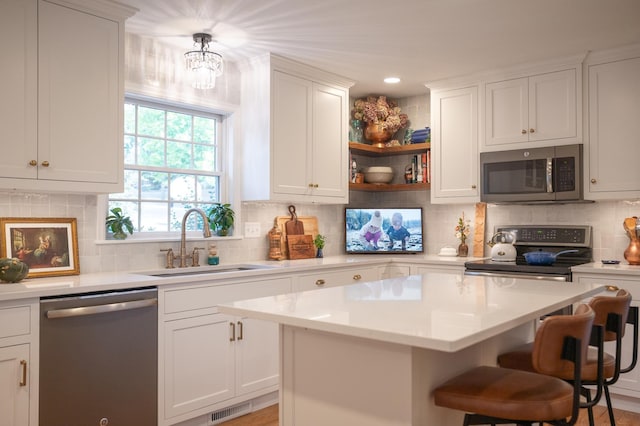 kitchen with appliances with stainless steel finishes, a sink, light countertops, a breakfast bar area, and visible vents