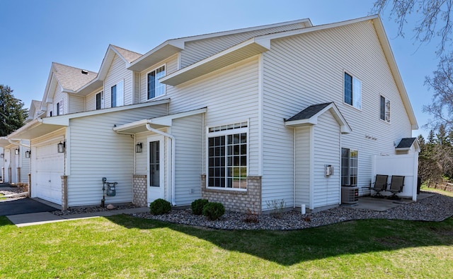 view of front of property with a front lawn, central AC unit, driveway, and a garage