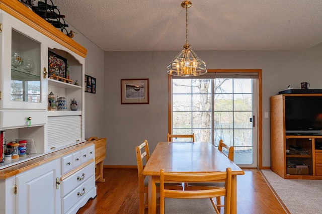 dining room featuring an inviting chandelier, a textured ceiling, and light wood-style flooring