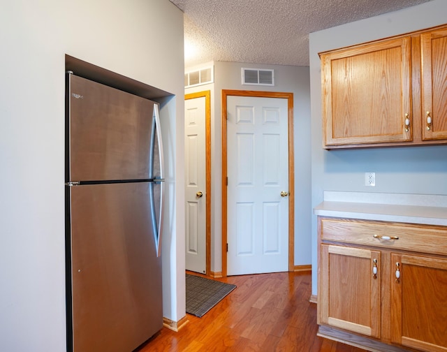 kitchen featuring freestanding refrigerator, light countertops, light wood-style floors, and visible vents