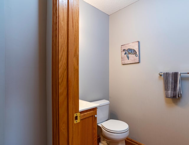 bathroom featuring toilet, vanity, and a textured ceiling
