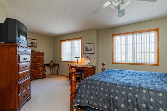 bedroom featuring baseboards, light carpet, a ceiling fan, and a textured ceiling