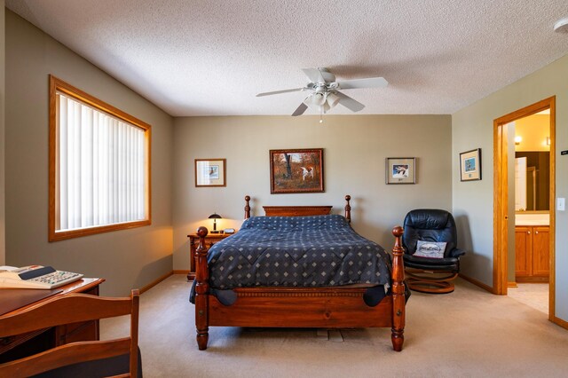 carpeted bedroom with ensuite bath, baseboards, ceiling fan, and a textured ceiling
