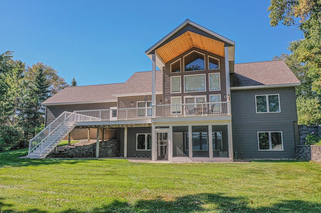 rear view of property with a yard, stairway, a sunroom, and a shingled roof