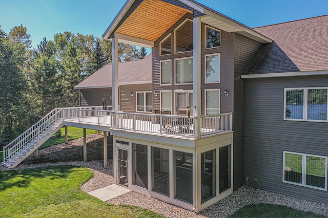 rear view of house with a sunroom, a yard, a shingled roof, and stairway