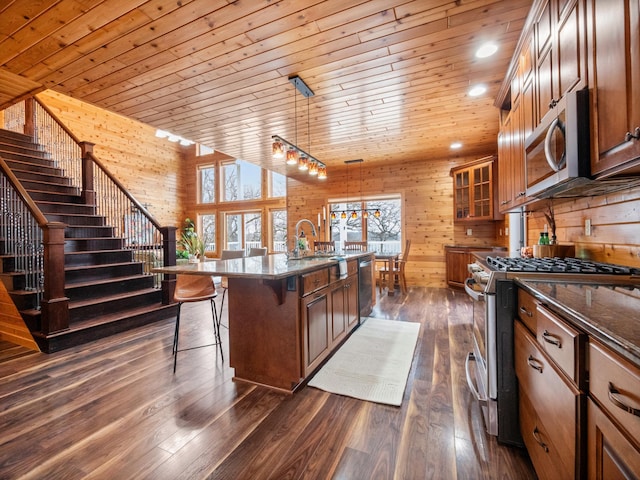 kitchen featuring wooden ceiling, wooden walls, a sink, and appliances with stainless steel finishes