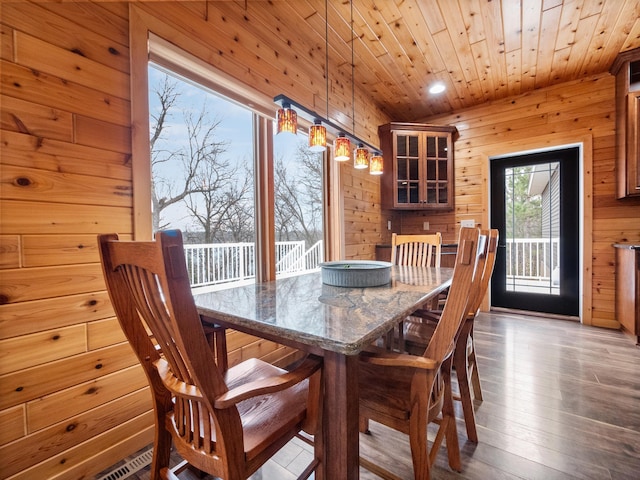 dining room with wood finished floors, wooden walls, wooden ceiling, and recessed lighting