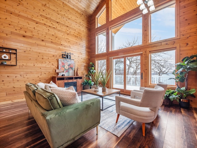 living area featuring hardwood / wood-style flooring, wood walls, and high vaulted ceiling