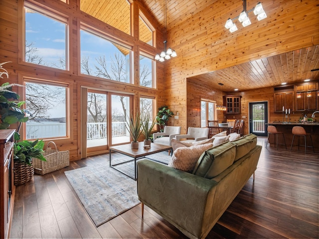 living area featuring wood ceiling, a high ceiling, dark wood-style flooring, and wooden walls