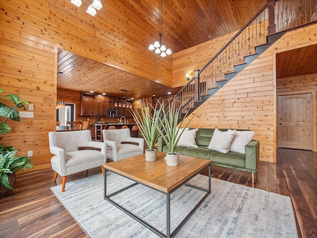 living area featuring a chandelier, wooden walls, a towering ceiling, and stairs