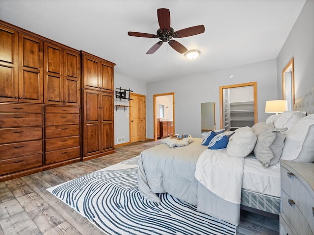 bedroom with visible vents, a ceiling fan, a walk in closet, light wood-style floors, and ensuite bathroom