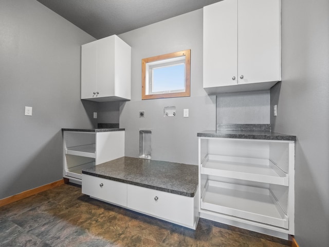 kitchen featuring white cabinets, dark countertops, and baseboards