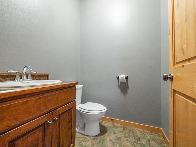 bathroom with toilet, vanity, and baseboards