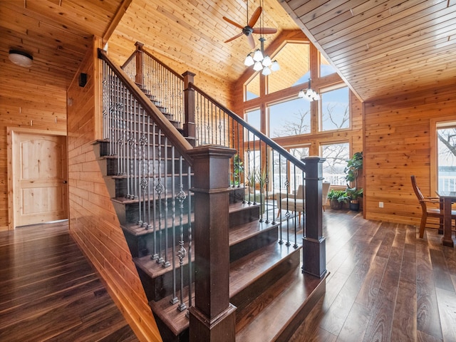 staircase with wood walls, wood ceiling, hardwood / wood-style flooring, high vaulted ceiling, and ceiling fan with notable chandelier