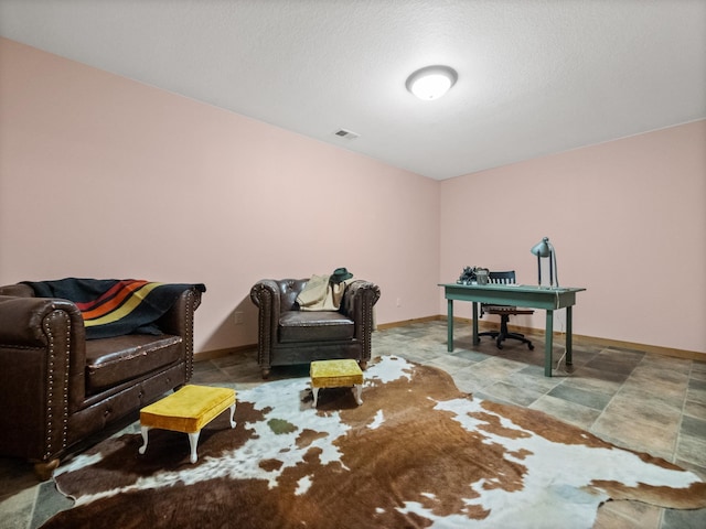 sitting room featuring stone finish flooring, baseboards, and visible vents