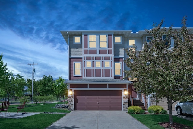 view of front facade featuring driveway, a front lawn, an attached garage, and stone siding