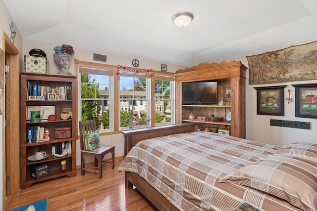 bedroom featuring light wood finished floors and vaulted ceiling
