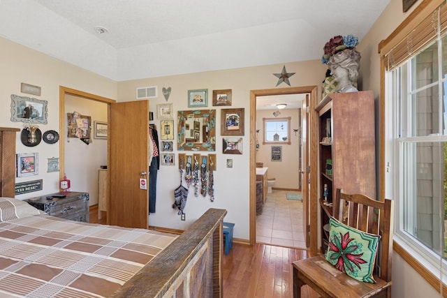 bedroom with hardwood / wood-style flooring and ensuite bath
