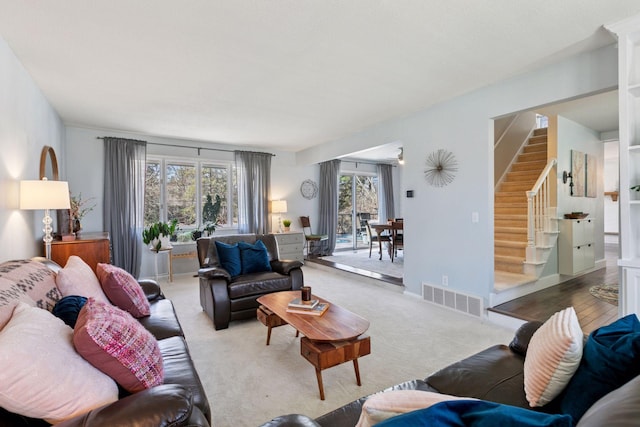 living area featuring carpet flooring, visible vents, and stairway
