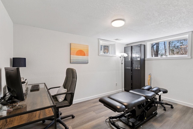 office area featuring visible vents, baseboards, wood finished floors, and a textured ceiling