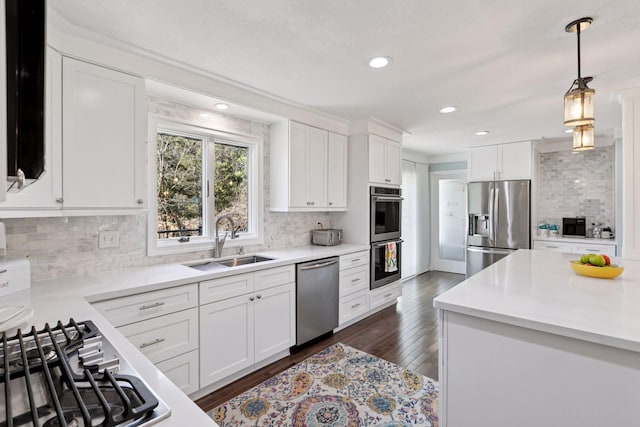 kitchen featuring stainless steel appliances, a sink, white cabinetry, and tasteful backsplash