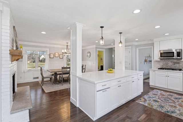 kitchen featuring stainless steel microwave, recessed lighting, white cabinetry, and a fireplace