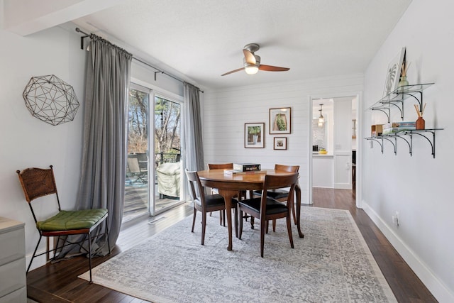 dining space featuring baseboards, a ceiling fan, and dark wood-type flooring