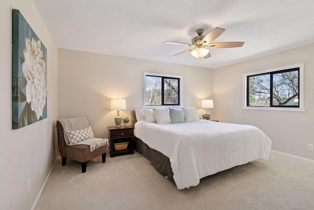 bedroom with a ceiling fan, baseboards, and light colored carpet
