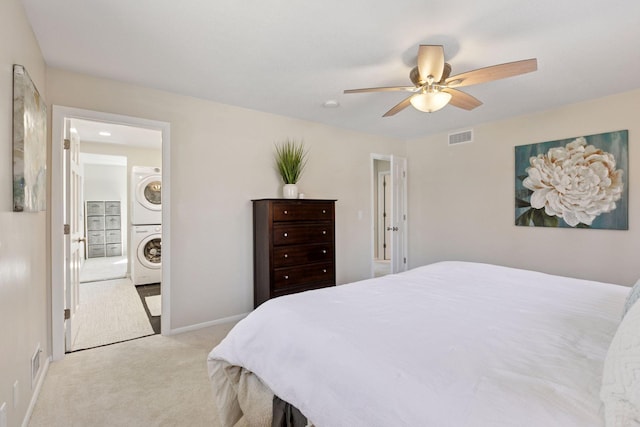 carpeted bedroom featuring baseboards, visible vents, a ceiling fan, and stacked washer / dryer