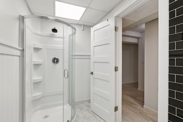 bathroom with a shower stall, baseboards, and a wainscoted wall