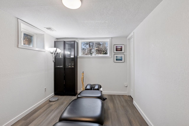 workout area featuring baseboards, wood finished floors, and a textured ceiling