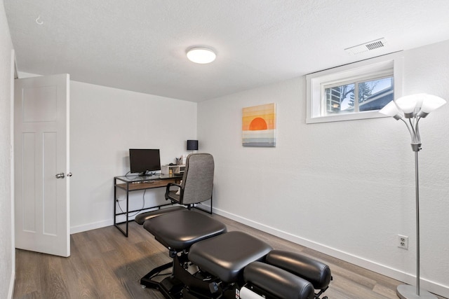 home office featuring baseboards, wood finished floors, visible vents, and a textured ceiling