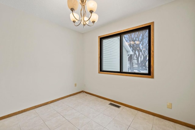 empty room featuring light tile patterned floors, visible vents, baseboards, and an inviting chandelier
