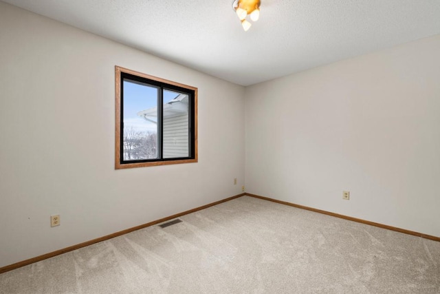 spare room featuring a textured ceiling, baseboards, visible vents, and carpet floors