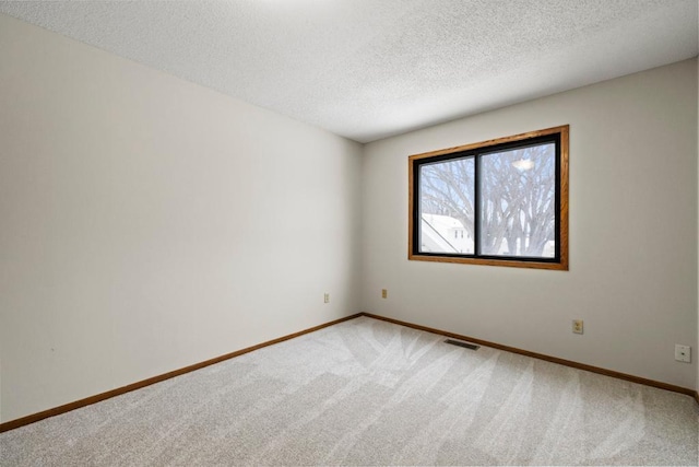 empty room featuring visible vents, baseboards, light colored carpet, and a textured ceiling