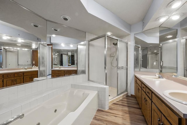 full bathroom featuring a sink, a shower stall, a jetted tub, and wood finished floors