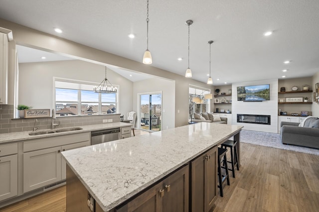 kitchen featuring a sink, dishwasher, open floor plan, a large fireplace, and recessed lighting