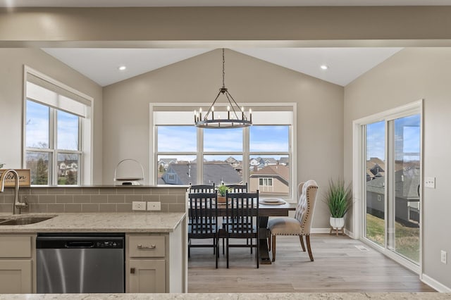 kitchen featuring stainless steel dishwasher, a sink, lofted ceiling, light wood-style flooring, and a chandelier