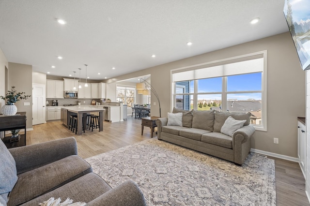living area featuring light wood-style floors, baseboards, and recessed lighting