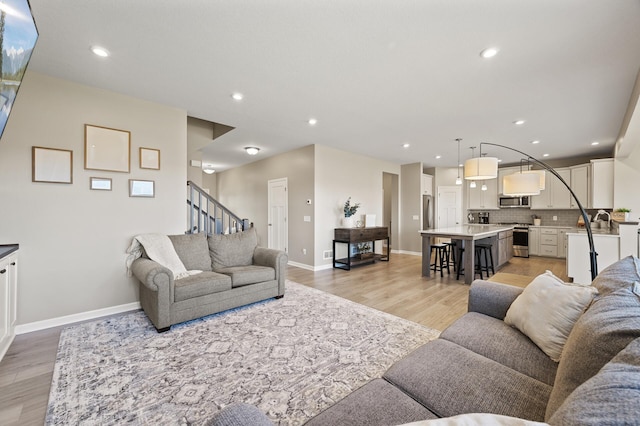 living room with light wood finished floors, baseboards, stairs, and recessed lighting