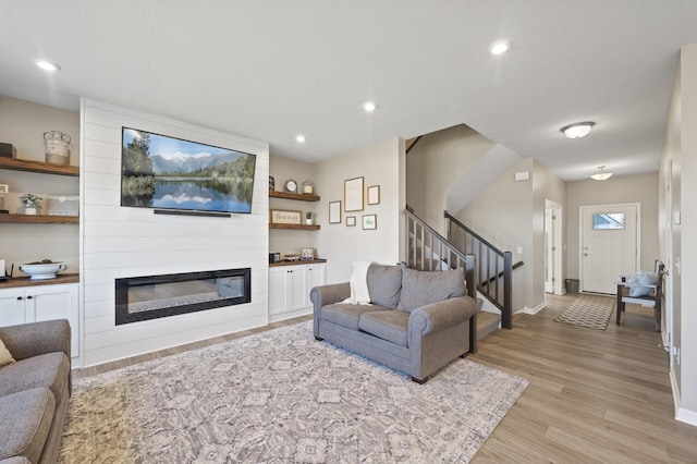living room featuring light wood-style floors, stairs, a fireplace, baseboards, and recessed lighting