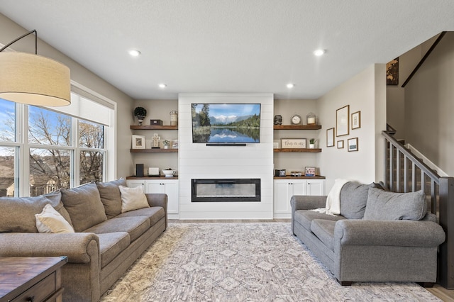 living room featuring stairs, recessed lighting, a fireplace, and light wood-style floors