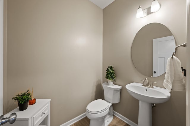 half bathroom with wood finished floors, baseboards, and toilet