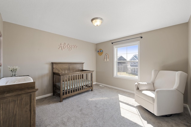carpeted bedroom with baseboards and a nursery area