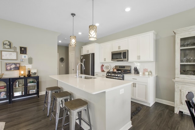 3459 109th Ln NE, Blaine, MN 55449 - kitchen featuring appliances with stainless steel finishes, a sink, dark wood-type flooring, a center island with sink, and a kitchen breakfast bar