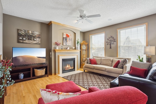 living room with a glass covered fireplace, a textured ceiling, a ceiling fan, and wood finished floors