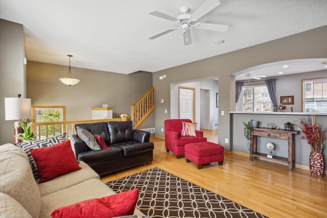 living area featuring a textured ceiling, a ceiling fan, baseboards, wood finished floors, and visible vents