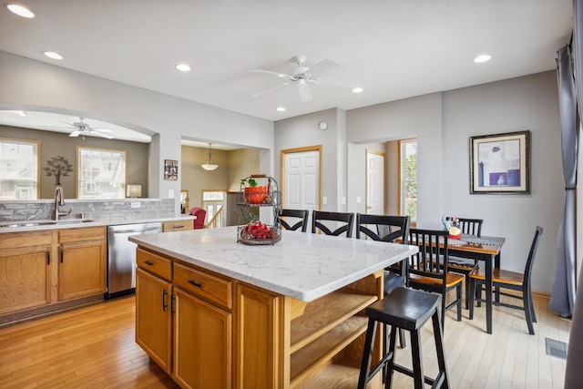 kitchen featuring ceiling fan, a breakfast bar area, a center island, a sink, and dishwasher