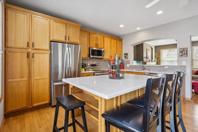 kitchen featuring arched walkways, appliances with stainless steel finishes, backsplash, and a kitchen island