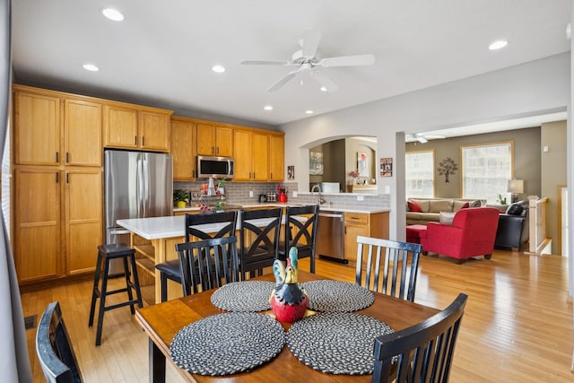 dining room with a ceiling fan, arched walkways, recessed lighting, and light wood-type flooring